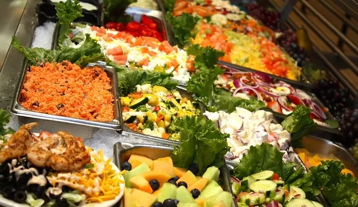 Fresh salad bar at C&H Cafeteria with carrot salad, garden salad, fruit and cucumbers